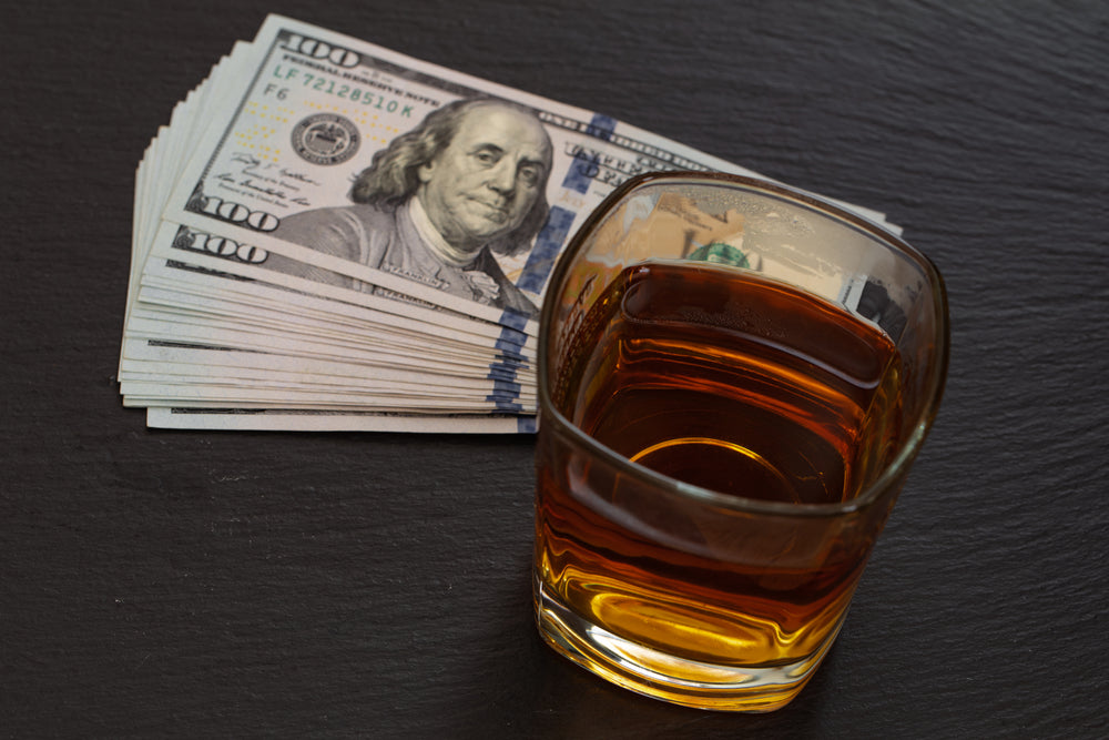 A glass of whisky neat and a pile of American dollars.