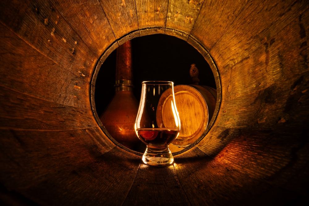 A open, empty barrel with a Glencairn glass of neat whisky.