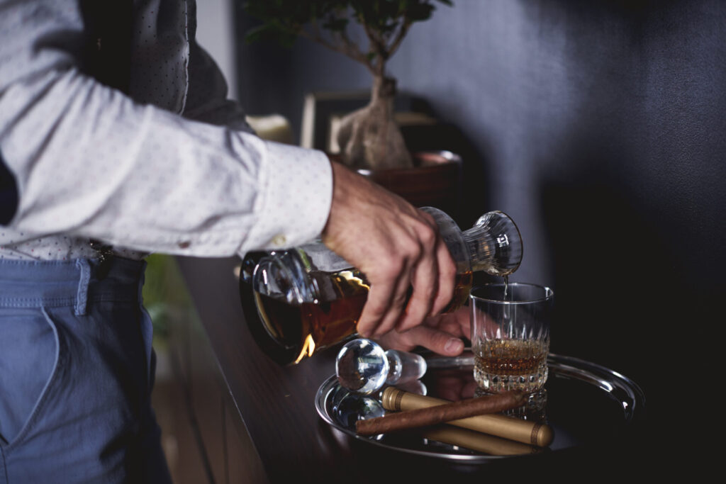 A man pouring a glass of neat whisky.