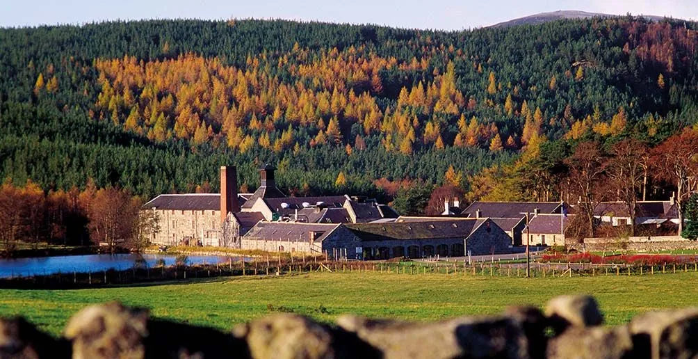 an image of Royal Lochnagar distillery from a distance surround by nature