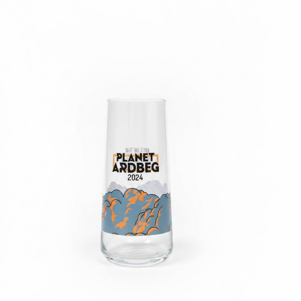 A clear glass tumbler with a printed design reading 'PLANET ARDBEG 2025' and a blue-gray mountain illustration with orange accents, standing on a textured beige carpet against a light wall.