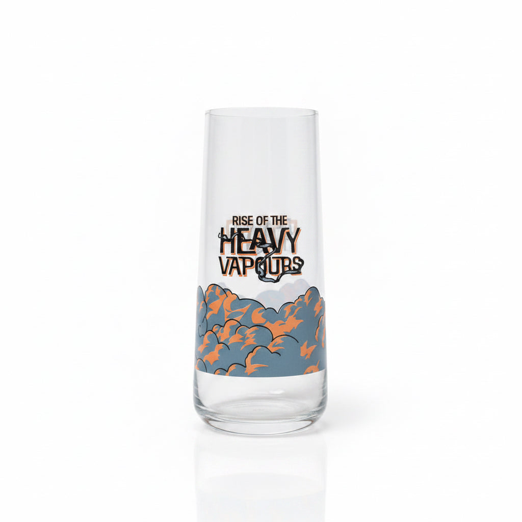 A clear glass tumbler with a printed graphic that reads 'RISE OF THE HEAVY VAPORS' above an orange and blue cloud illustration, standing on a beige carpet against a light gray wall.