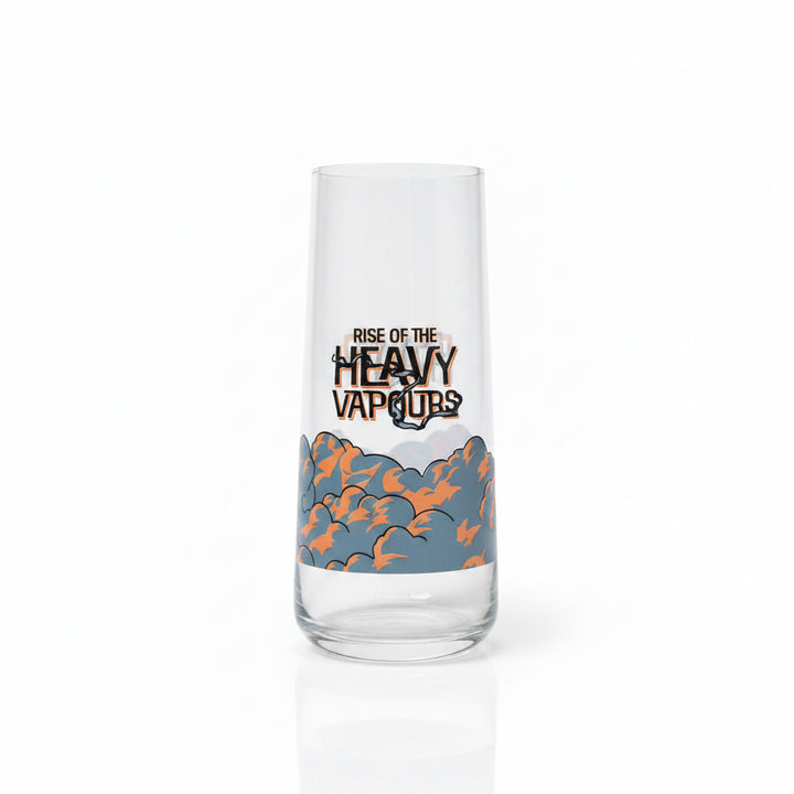 A clear glass tumbler with a printed graphic that reads 'RISE OF THE HEAVY VAPORS' above an orange and blue cloud illustration, standing on a beige carpet against a light gray wall.