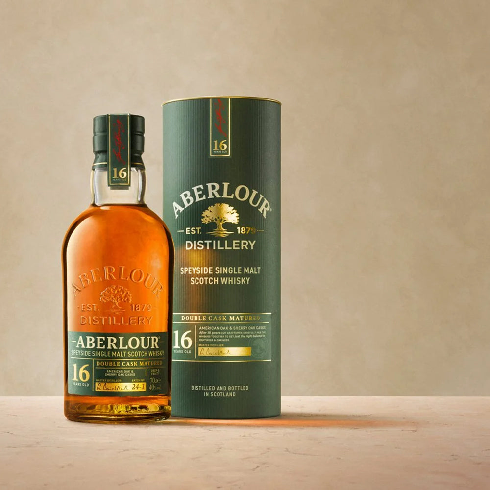 A bottle of Aberlour 16 Year Old Double Cask Single Malt Scotch Whisky stands beside its matching cylindrical box on a neutral background, both with gold and white labels accented with green, emphasizing its double cask maturation.