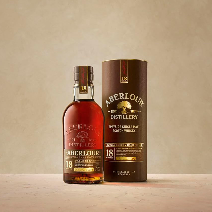 A bottle of Aberlour 18 Year Old Single Malt Scotch Whisky stands next to its brown cylindrical box on a stone surface with a light beige background.