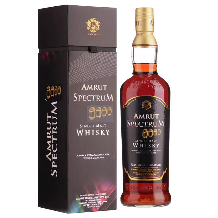 A bottle of Amrut Spectrum Indian Single Malt Whisky stands beside its black and gold box. The label highlights its unique maturation in a special cask crafted from diverse oak woods.