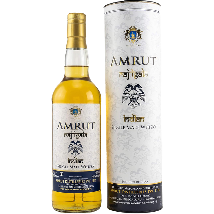 A bottle of Amrut Raj Igala Indian Single Malt Whisky is displayed beside its cylindrical packaging, both featuring a gold and white label with blue accents, a branded crest, and a bold black eagle illustration.
