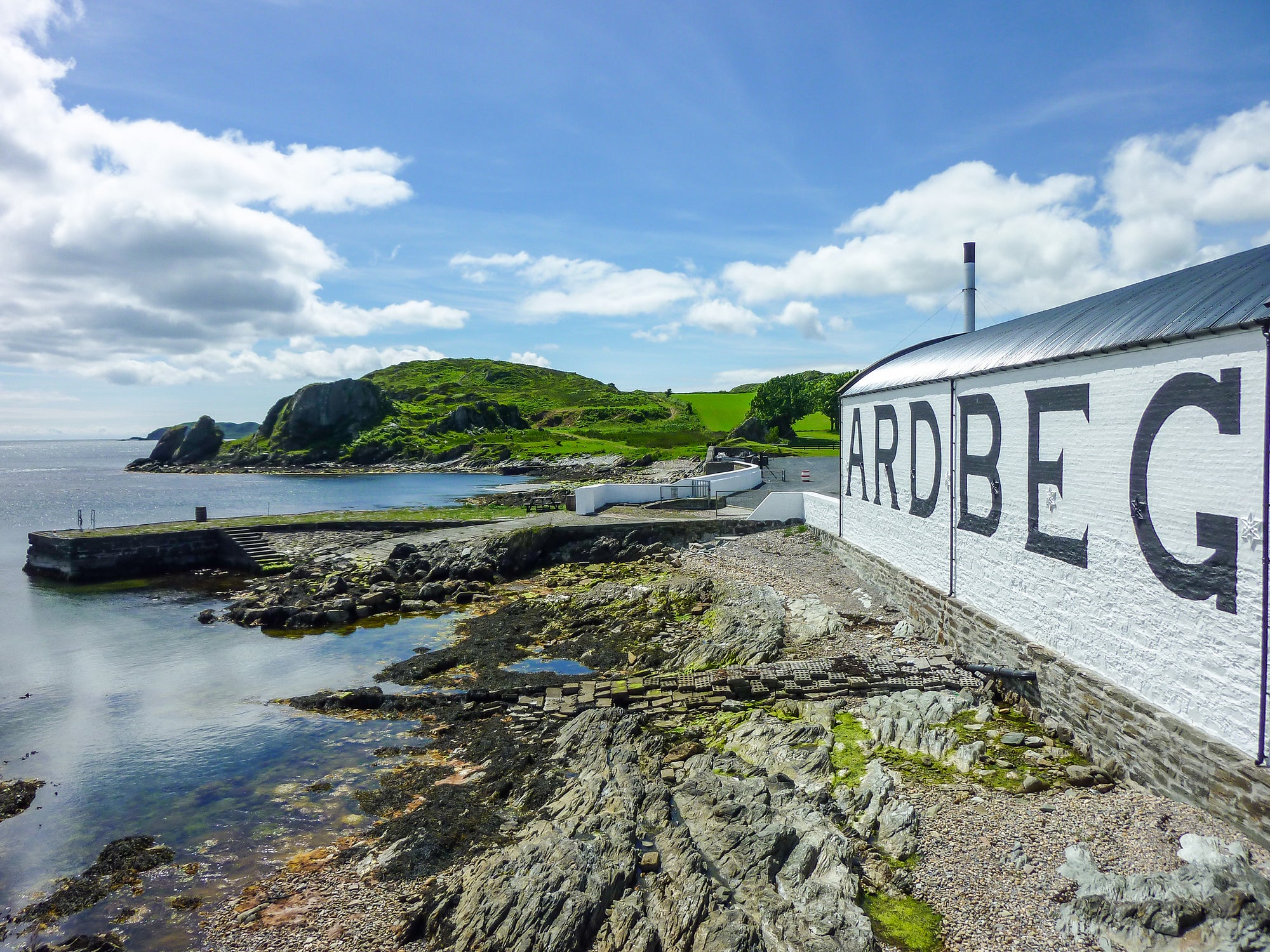 Ardbeg distillery building by a coastal landscape with clear skies