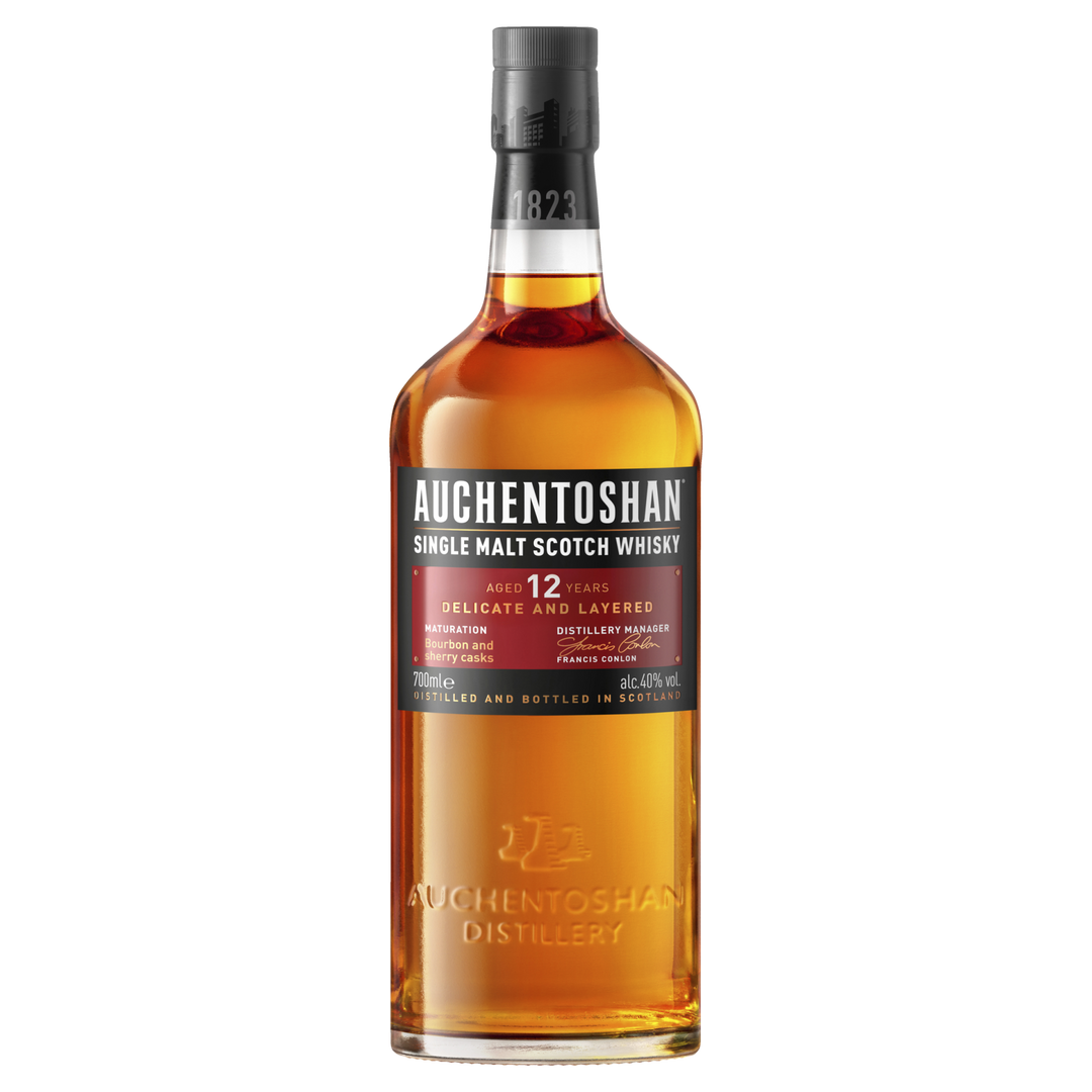 A bottle of Auchentoshan 12 Year Old Single Malt Scotch Whisky features a black cap, amber liquid, and a red and white label displaying triple distilled details, age, flavor notes, and distillery information.