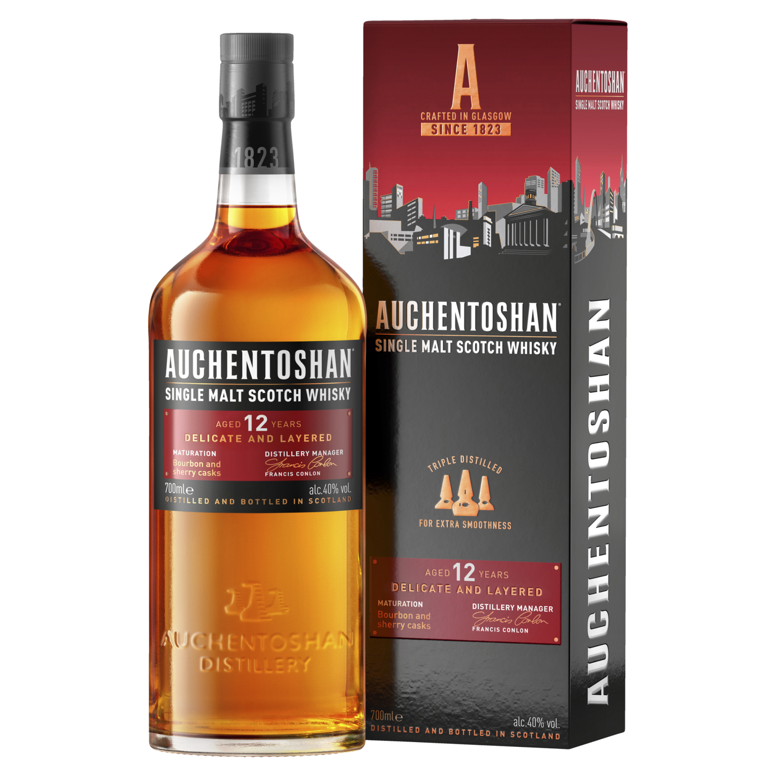 Auchentoshan 12 Year Old Single Malt Scotch Whisky stands beside its branded box, both with orange and white accents that emphasize its Scottish heritage and signature triple distillation.