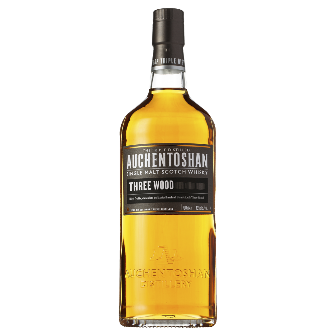 A bottle of Auchentoshan Three Wood Single Malt Scotch Whisky with a black label, gold accents, and amber liquid is shown against a plain white background, highlighting its signature triple maturation process.