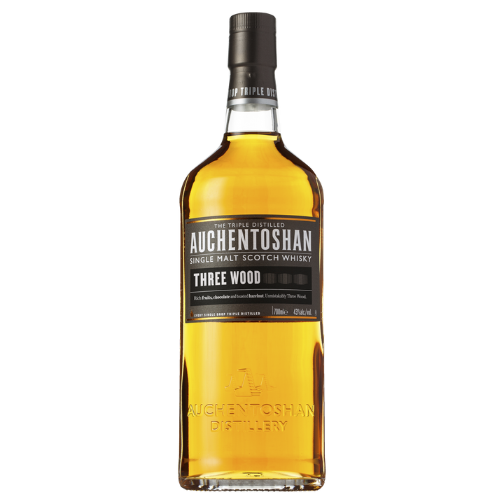A bottle of Auchentoshan Three Wood Single Malt Scotch Whisky with a black label, gold accents, and amber liquid is shown against a plain white background, highlighting its signature triple maturation process.