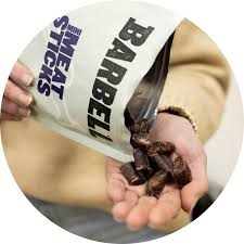 Person holding a bag labeled 'SHEAT STICKS' with a barbell and protein powder.