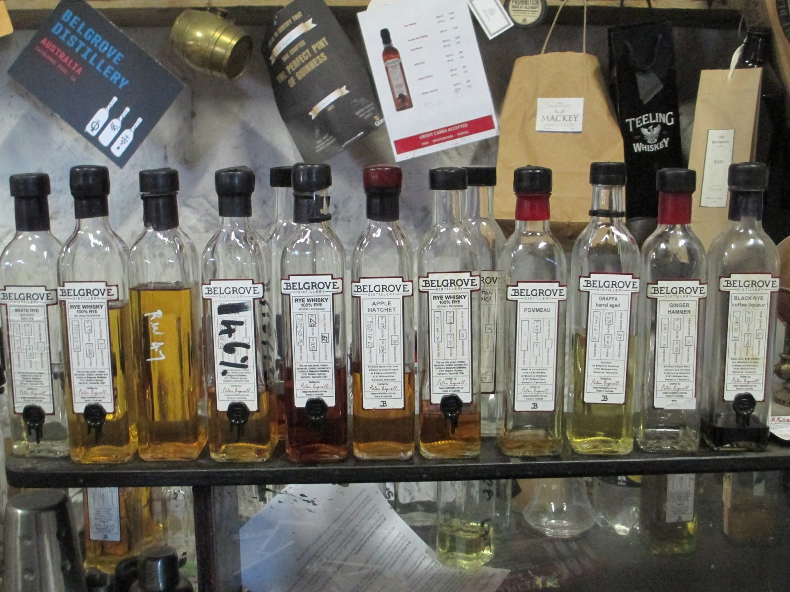 Row of Belgrove whiskey bottles on a shelf with various labels and packaging.