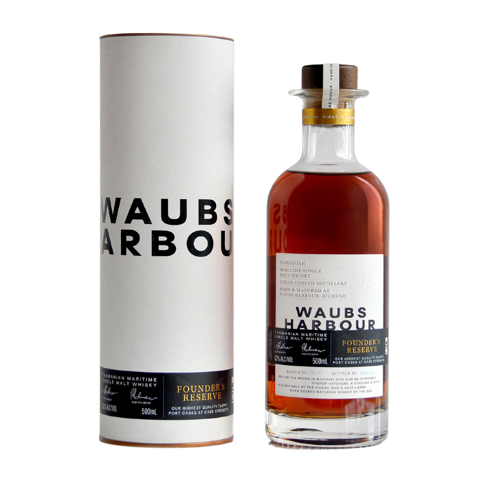 A bottle of Waubs Harbour Founders Reserve Tasmanian Single Malt Whisky stands beside its cylindrical white packaging with bold black lettering and gold accents, showcasing the amber spirit and its detailed label inspired by Tasmania’s maritime climate.