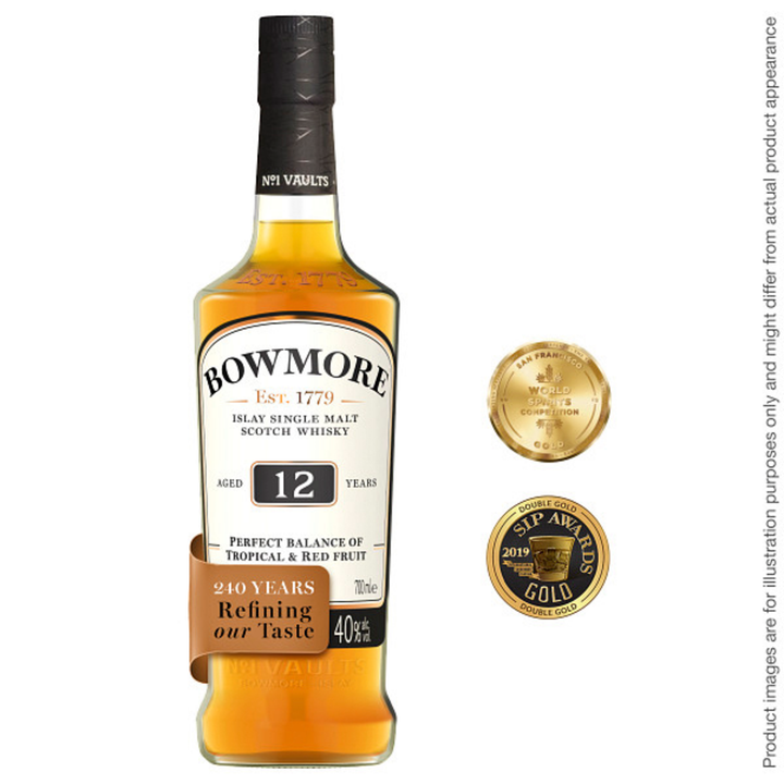 A bottle of Bowmore 12 Year Old Single Malt Scotch Whisky stands upright with its label visible. Two gold award medallions are beside the peated whisky. Fine print states the image is for illustration purposes only.