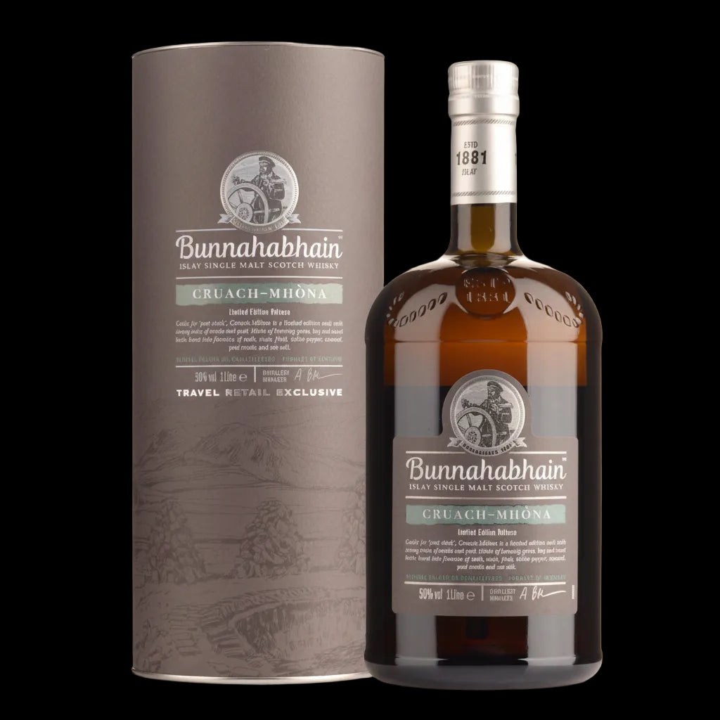 A bottle of Bunnahabhain Cruach-Mhóna 50% vol single malt Scotch whisky next to its tall cylindrical cardboard packaging box, both in a dark brown and gray color scheme with white and green accents.