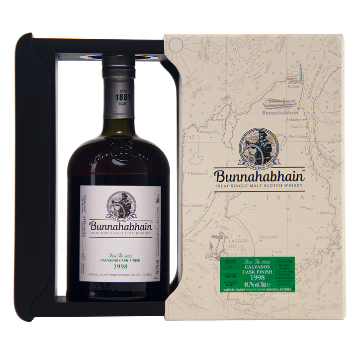 A bottle of Bunnahabhain Fèis Ìle 2022 1998 Calvados Cask Finish is presented in a cream map-themed box with a window that showcases the elegant label.