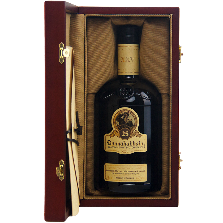 A bottle of Bunnahabhain XXV 25 Year Old Single Malt Scotch Whisky stands upright in an open wooden box lined with tan fabric, with a scroll attached to the left side of this limited edition presentation.