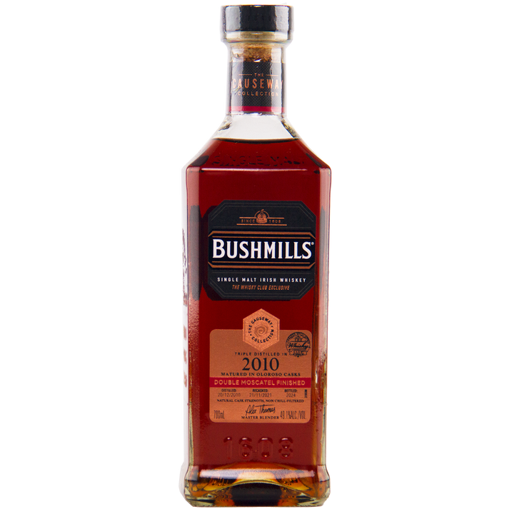 Bushmills 2010 Double Moscatel Cask Single Malt whisky from the Causeway Collection comes in a rectangular bottle with a black label, gold and copper accents, and a copper nameplate highlighting its double moscatel finish.