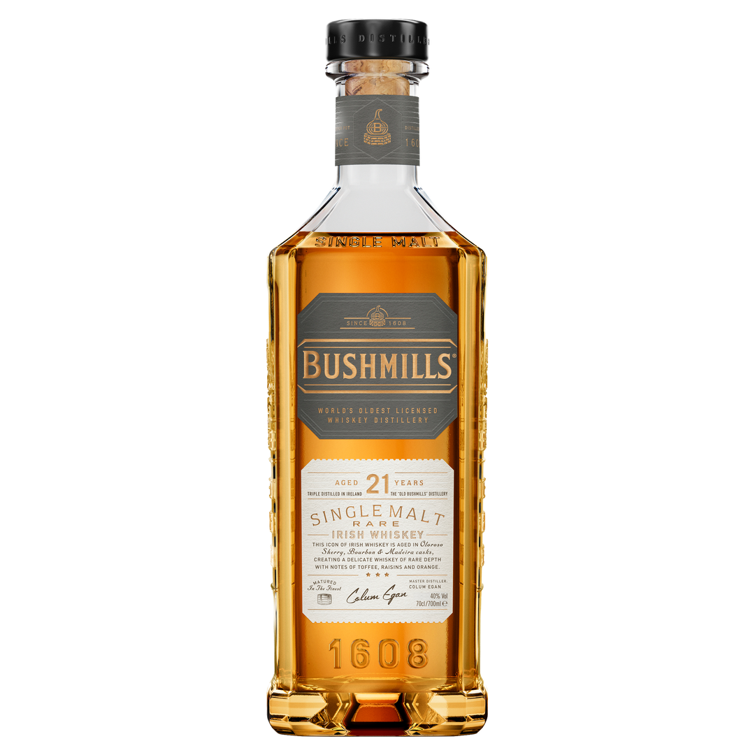 A bottle of Bushmills 21 Year Old Single Malt Irish Whiskey featuring golden amber liquid, ornate labeling, and "1608" embossed at the base.