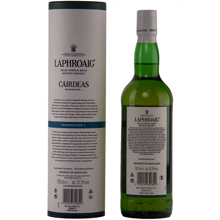 A bottle of Laphroaig Cairdeas 2022 Warehouse 1 Islay single malt stands beside its matching cylindrical box, both featuring black and green branding and descriptive text.
