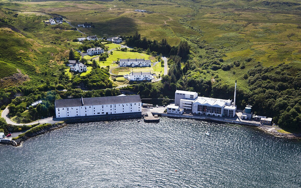 Aerial view of a coastal building complex with greenery and water in the foreground