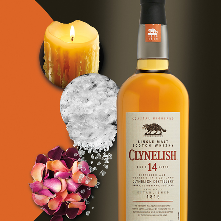 A bottle of Clynelish 14 Year Old Single Malt Whisky is displayed beside a lit yellow candle, coarse salt, and rose petals on an abstract orange and black background.