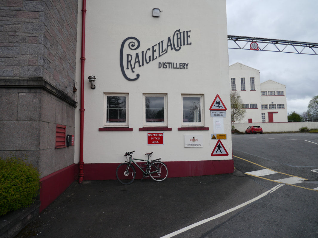 Craigeilachie Distillery building with a bicycle parked in front on a cloudy day.