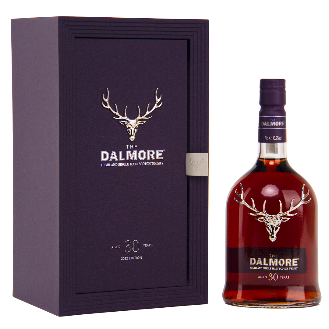 A bottle of The Dalmore 30 Year Old Single Malt Scotch Whisky stands next to its elegant dark purple box, both showcasing a silver stag logo and white text denoting the exclusive 2023 edition.