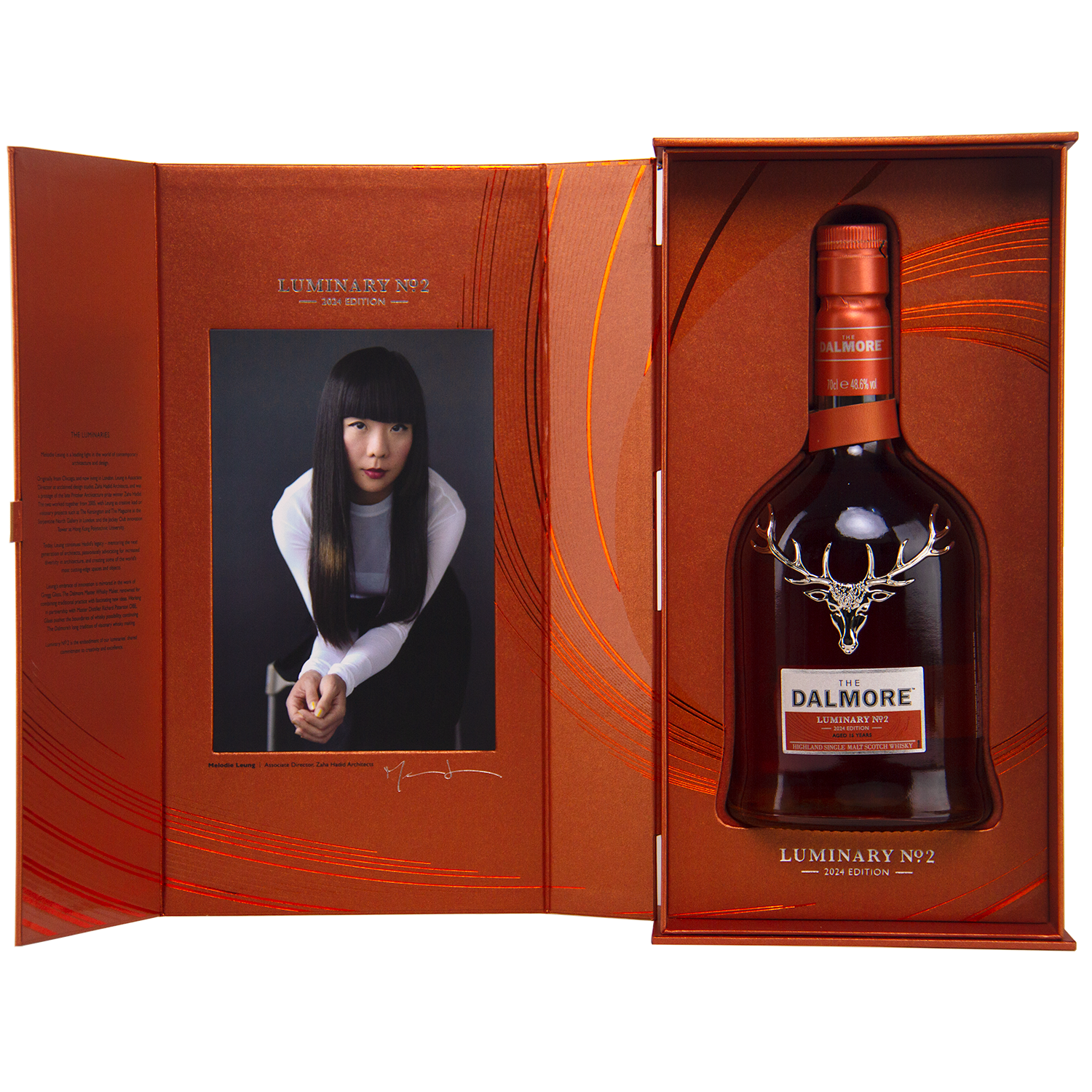 A gift box includes The Dalmore Luminary No. 2 16 Year Old Single Malt Scotch Whisky and a portrait photo of a woman with long black hair in a white and black outfit, set against an orange patterned background.