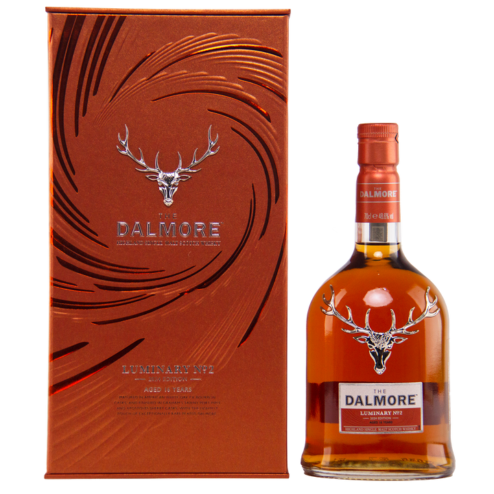 A bottle of The Dalmore Luminary No. 2 16 Year Old Single Malt Scotch Whisky stands beside its matching metallic orange box, both adorned with the silver stag logo and embossed patterns—capturing the essence of Dalmore’s luxury.