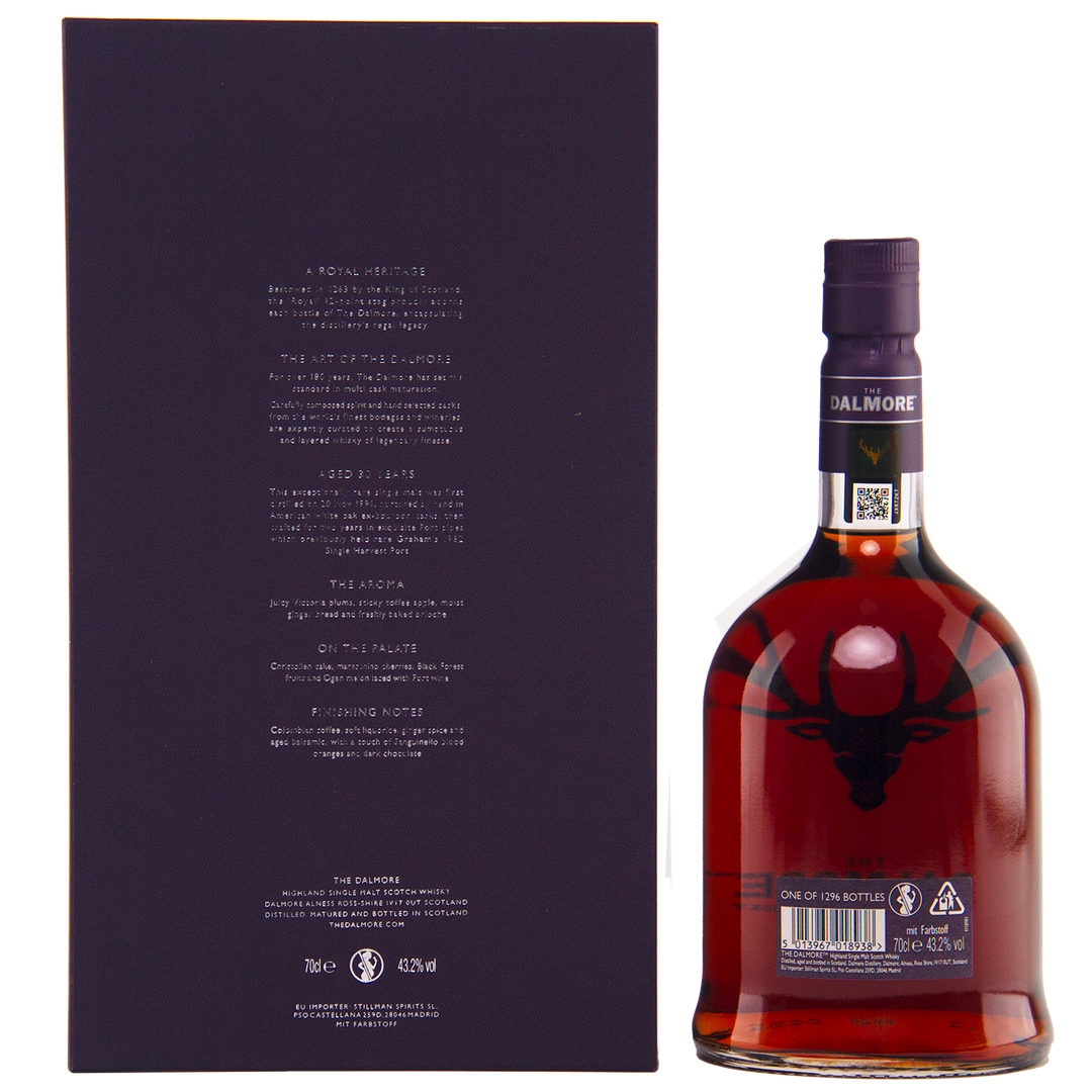 A bottle of The Dalmore 30 Year Old Single Malt Scotch with a dark cap and stag logo stands next to its tall, dark box with white back text—a luxurious whisky display.