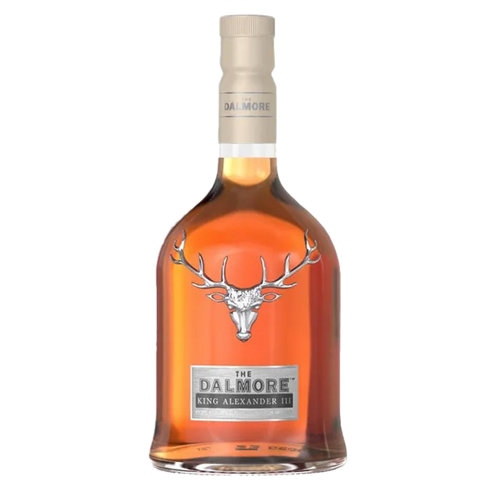 A bottle of The Dalmore King Alexander III Highland Single Malt Scotch Whisky, with a bronze liquid, beige cap, silver stag emblem, and the name below, showcases its famous six cask maturation on a plain white background.