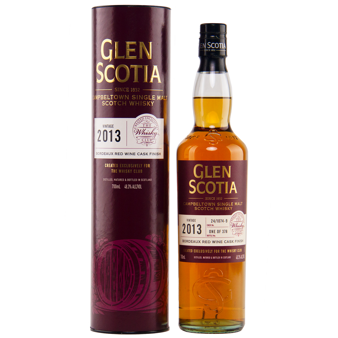 The Glen Scotia 2013 Bordeaux Single Cask bottle stands next to its maroon cylindrical packaging, both displaying gold and white text detailing its specifications, including maturation in a Bordeaux red wine cask.