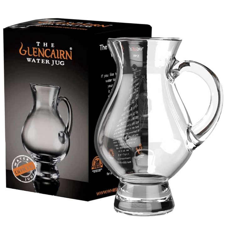 A clear Glencairn Crystal Water Jug sits beside its black box, which features an image of the jug and orange “The Glencairn Water Jug” branding—ideal for enhancing your whisky tasting experience.