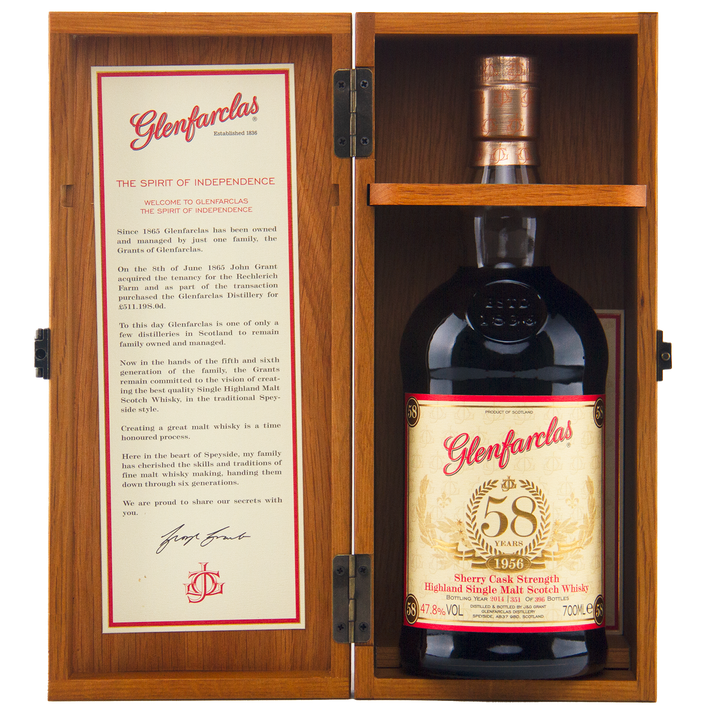 A bottle of Glenfarclas 1956 58 Year Old Sherry Cask Strength whisky is displayed in an open wooden box, with its description and history detailed on the inside of the left door.