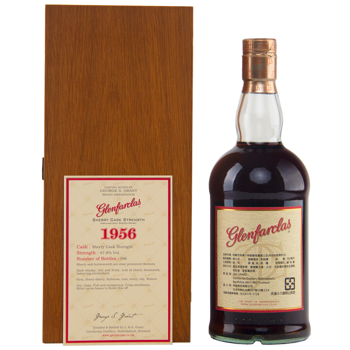 A bottle of Glenfarclas 1956 58 Year Old Sherry Cask Strength whisky is displayed beside a wooden box featuring a detailed label with its cask strength, vintage year, and limited release details.