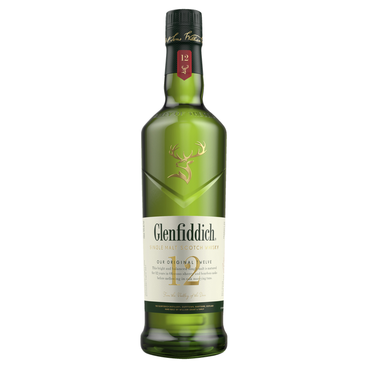 A green bottle of Glenfiddich 12 Year Old Single Malt Scotch Whisky with a gold stag logo and cream label stands upright on a white background, representing this classic Speyside whisky known for its smooth, distinctive flavor.