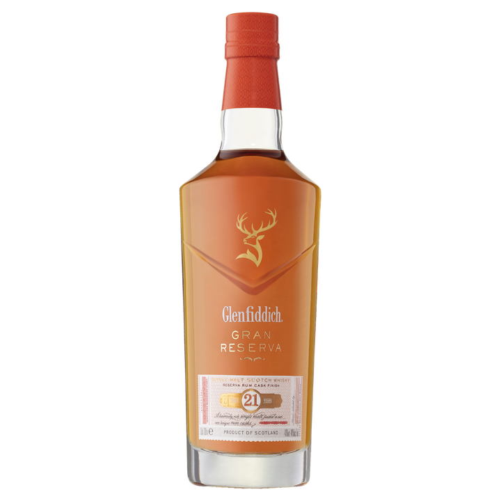 A bottle of Glenfiddich 21 Year Old Gran Reserva Single Malt Scotch Whisky, finished in Caribbean rum casks, featuring a red cap, gold stag logo, and a white-and-gold label on a clear background.