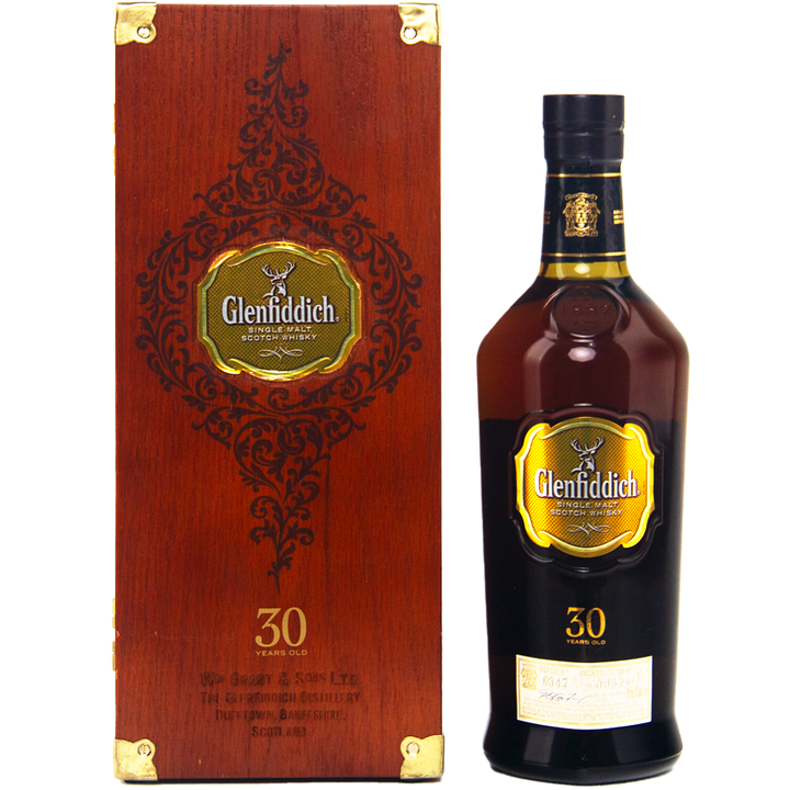 A bottle of Glenfiddich 30 Year Old Single Malt Scotch Whisky stands beside its ornate wooden box, both with gold labels and intricate detailing from the acclaimed Speyside distillery.