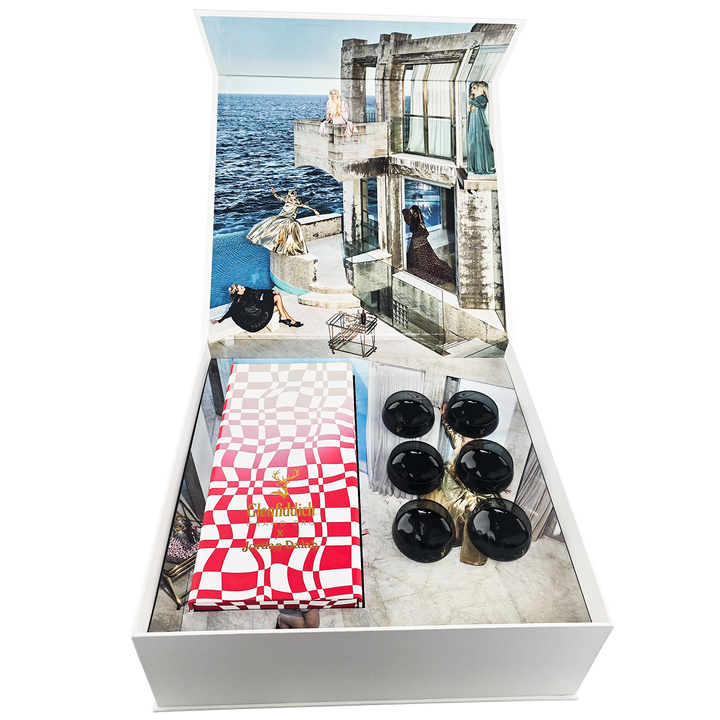 The Glenfiddich Grand Cru 23 Year Old x Jordan Dalah Box Set features six black spheres, a red and white checker-patterned booklet, and a stylish seaside backdrop—an exclusive release for discerning single malt whisky collectors.