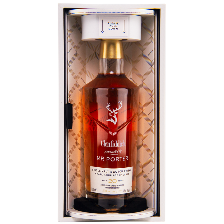 A bottle of Glenfiddich Mr. Porter 20 Year Old Single Malt Scotch Whisky stands upright in an elegant box with a plaid-patterned interior and a “PLEASE PULL DOWN” note, celebrating this exclusive MR PORTER collaboration.