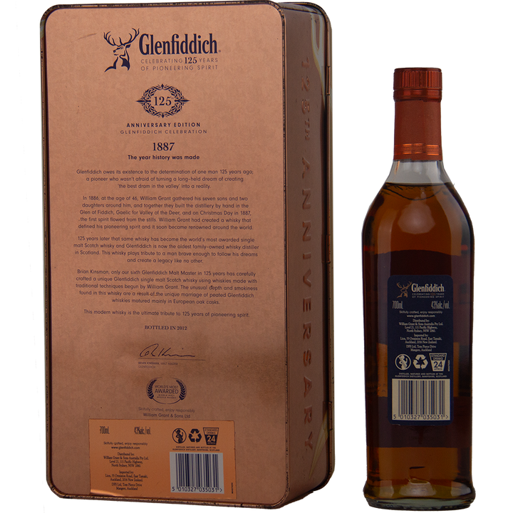 A Glenfiddich 125th Anniversary Edition Single Malt Scotch Whisky bottle is displayed next to its ornate tin box, showcasing detailed branding, distillery history, and notes on European oak cask maturation.