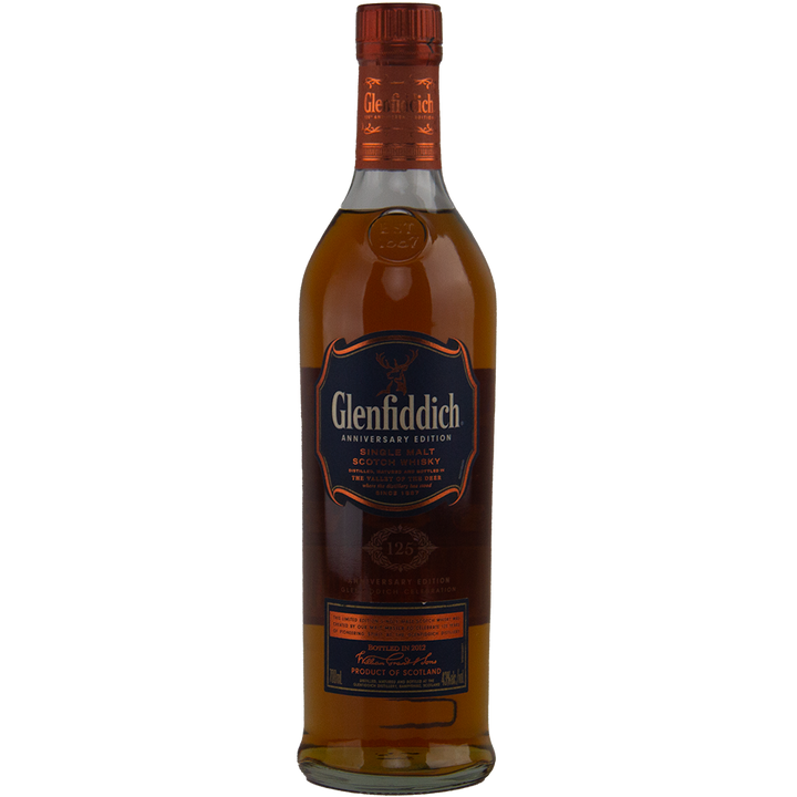 A bottle of Glenfiddich 125th Anniversary Edition Single Malt Scotch Whisky with dark amber liquid, a blue and gold label, and an orange cap. Matured in European oak casks to celebrate Glenfiddich’s milestone anniversary.