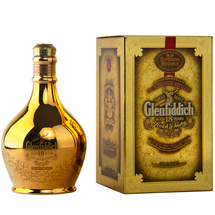 A gold-colored bottle of Glenfiddich 18 Year Old Superior Reserve Single Malt Scotch Whisky stands beside its ornate gold and brown box, both adorned with designs and text highlighting the whisky’s age and superior quality.