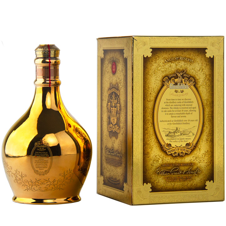 A golden, reflective bottle of Glenfiddich 18 Year Old Superior Reserve Single Malt Scotch Whisky stands by its ornate, gold-accented box adorned with detailed text and decorative designs on a light background.