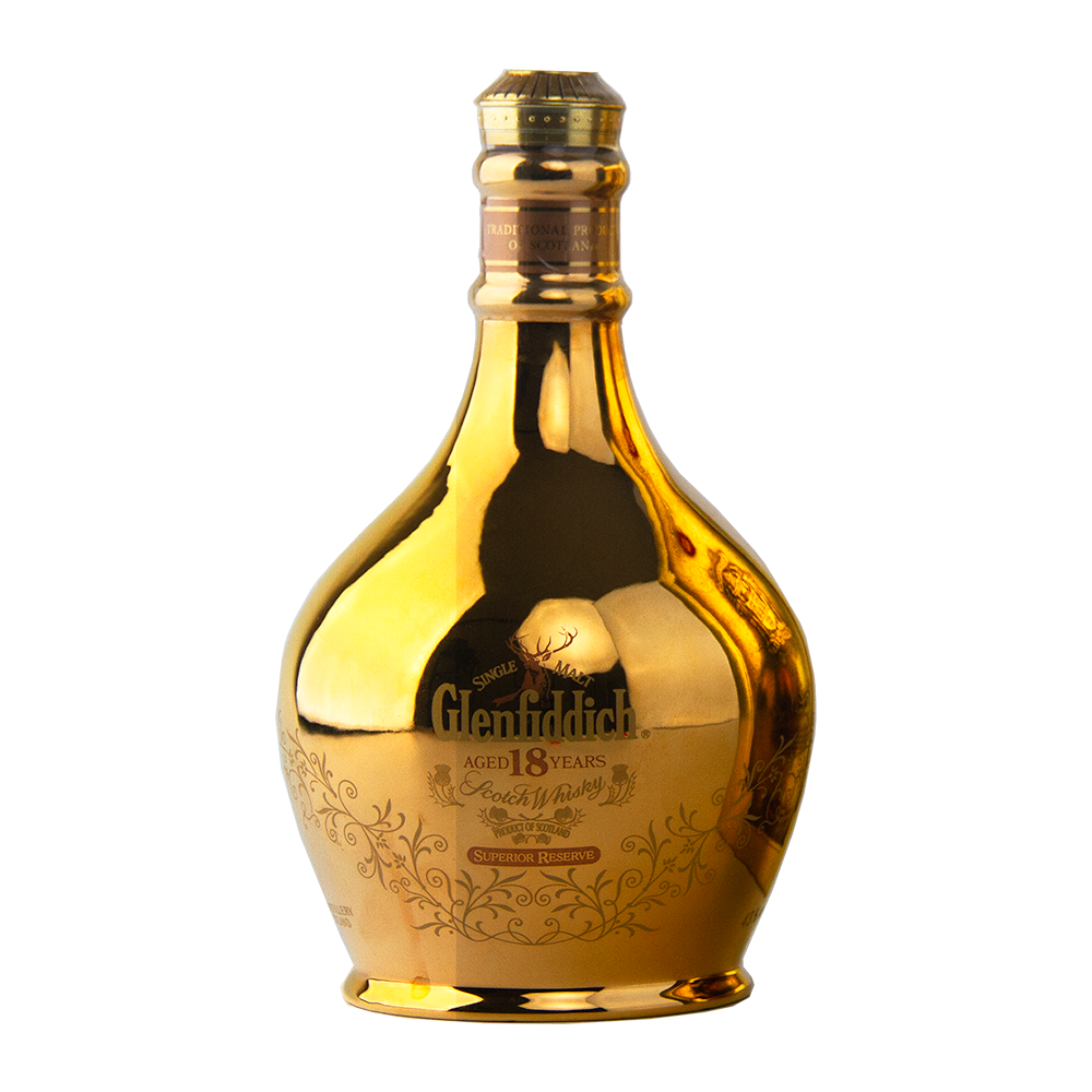 A gold, reflective ceramic decanter of Glenfiddich 18 Year Old Superior Reserve Single Malt Scotch Whisky features ornate detailing and a wide base tapering to a narrow neck, set against a plain white background.
