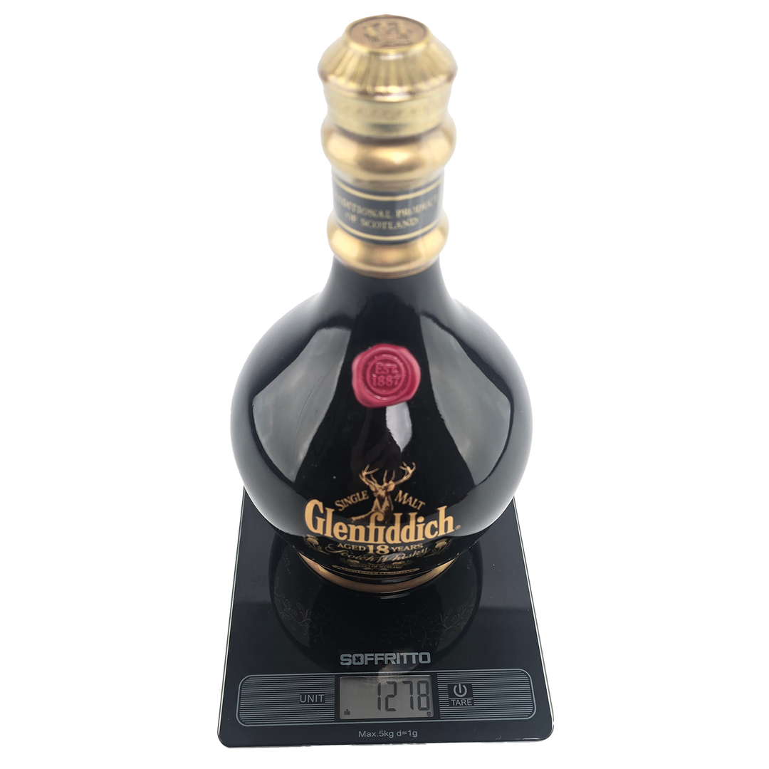 A bottle of Glenfiddich 18 Year Old Ancient Reserve Single Malt Scotch Whisky sits on a digital scale showing 1278g. With gold and red accents on its neck and label, this limited edition is a collectible decanter.