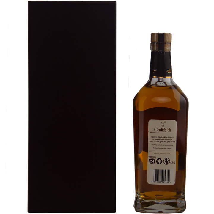 A bottle of Glenfiddich 40 year old 1977 Rare Vintage Single Malt Scotch Whisky with a gold cap stands beside a tall, plain black box. The back label shows product info and recycling symbols from this rare collection.